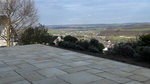 A stone patio with a view of a town and distant hills.