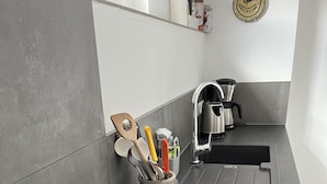 A modern kitchen with a black induction cooktop, a coffee maker, and a utensil holder on the counter.