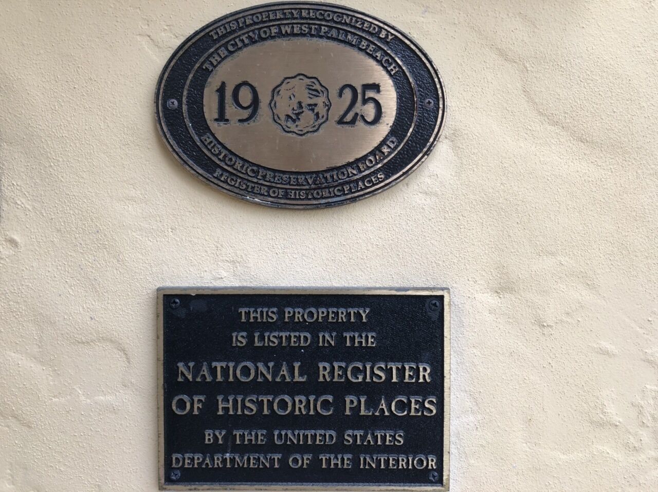 Twee plaquettes op een muur, waarvan één de 25e verjaardag van het Historic Preservation Board van West Palm Beach herdenkt, en de andere aangeeft dat het pand is opgenomen in het National Register of Historic Places door het Amerikaanse ministerie van Binnenlandse Zaken.