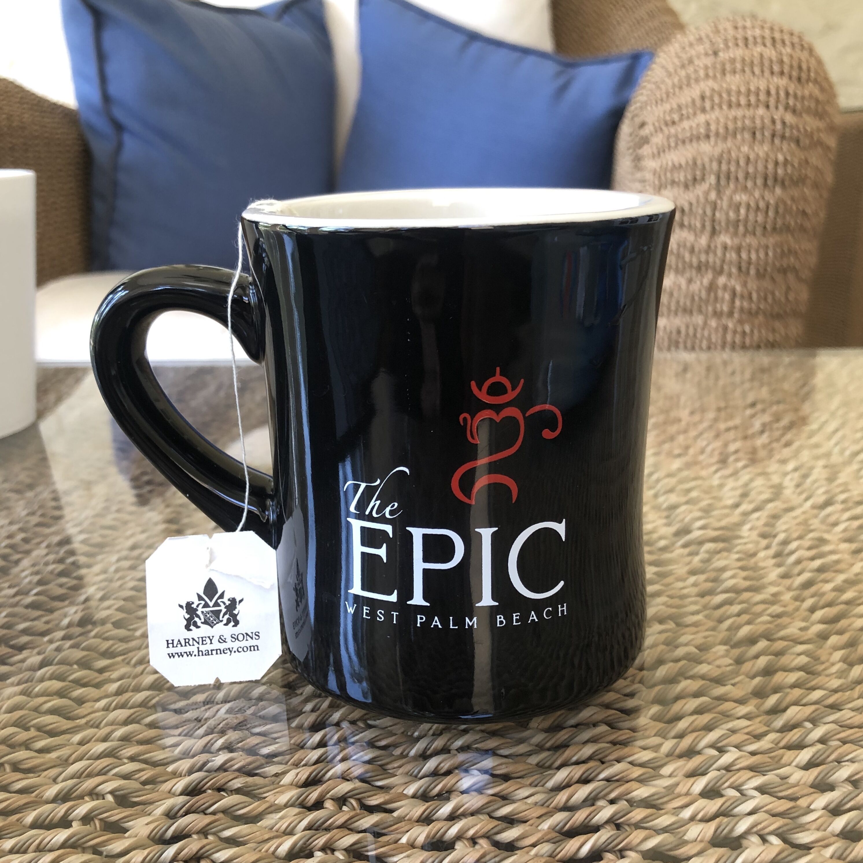 Eine schwarze Tasse mit dem Schriftzug "The EPIC West Palm Beach" und einem Teebeutelaufhänger.