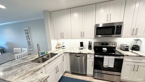 A modern kitchen with white cabinets, stainless steel appliances, and a marble countertop. - Oceanfront townhouse, 2 bedroom, 2.5 baths. (St. Augustine)