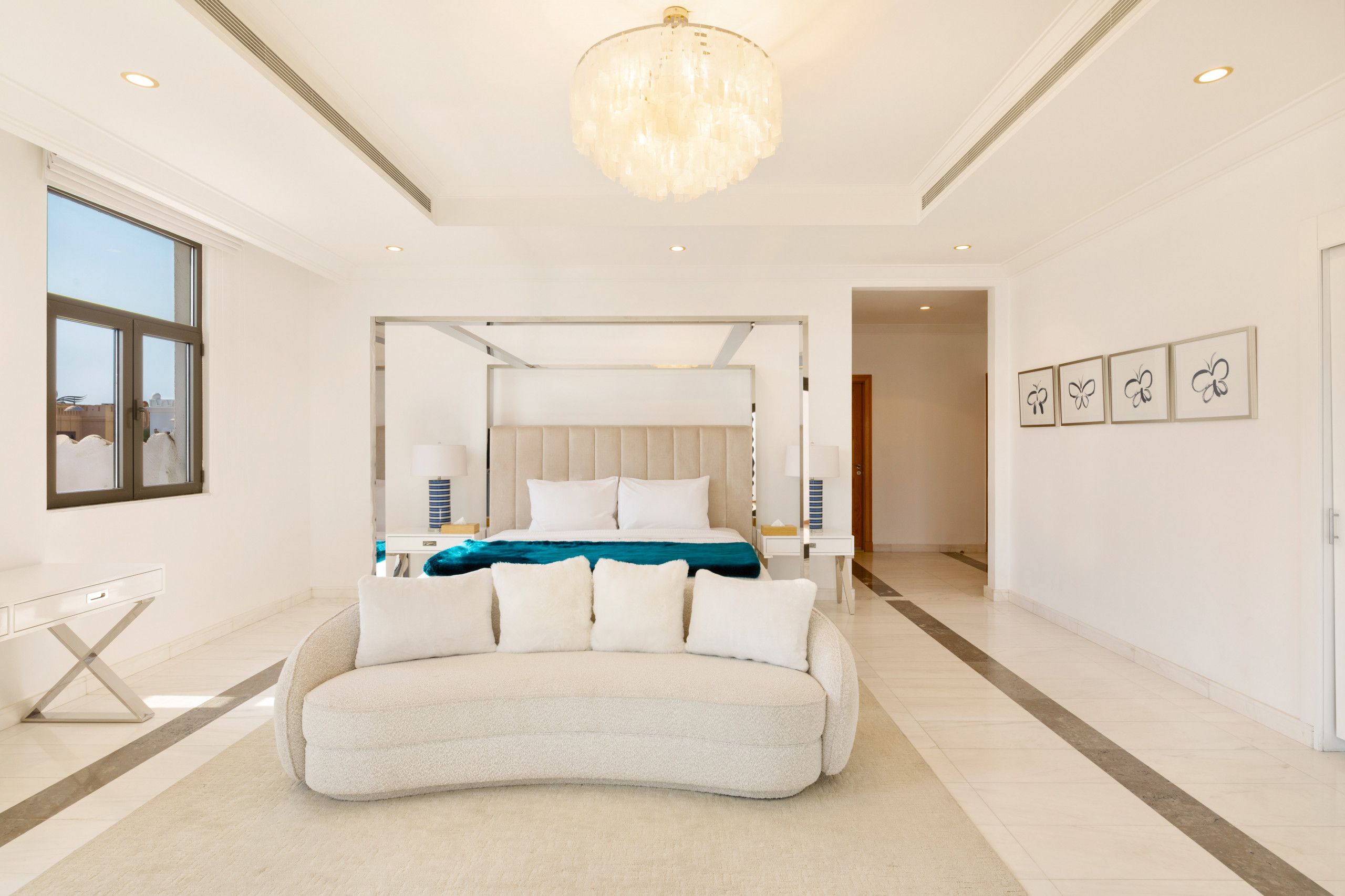 Een moderne slaapkamer met een groot bed, een wit bureau en een kroonluchter.