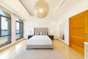 A bedroom with a large bed, a view of the sea, and a wooden door.