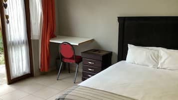A bedroom with a bed, a desk, and a chair.