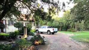 A white pickup truck parked on a cobblestone driveway leading to a house with a garden. - Cozy Guestrooms in Midrand (Midrand)