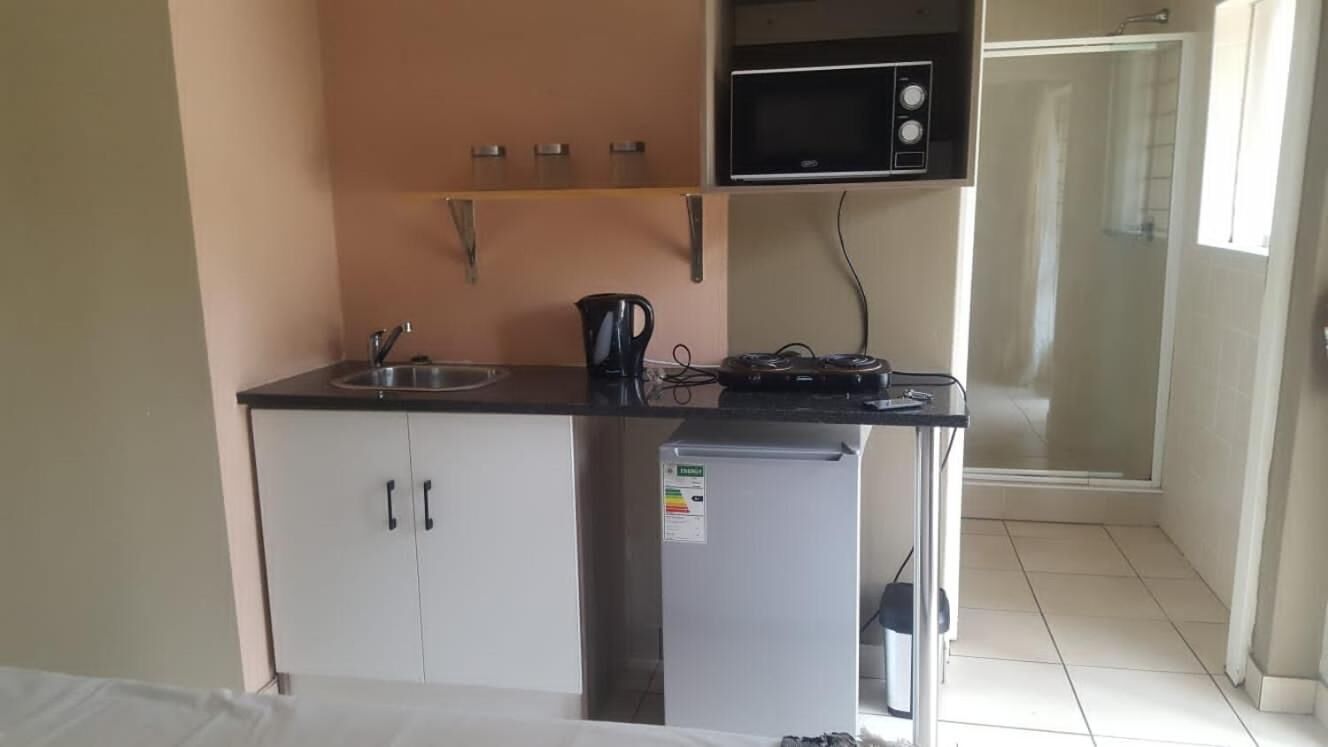 A compact kitchenette with a microwave, a small refrigerator, and a sink.