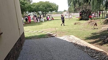 A paved pathway leading to a grassy area with a building on one side.