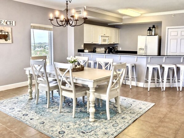 A kitchen with white cabinets, a dining table with chairs, and a chandelier.