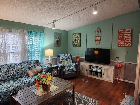 A living room with a sofa, armchair, coffee table, TV, and decorative items.