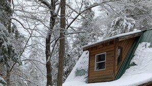 Una cabaña de madera con techo nevado y terraza de madera.
