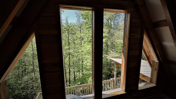 Una habitación con un ventanal grande con vistas a un área boscosa.
