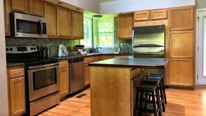 Una cocina moderna con armarios de madera, electrodomésticos de acero inoxidable y una isla grande con taburetes.