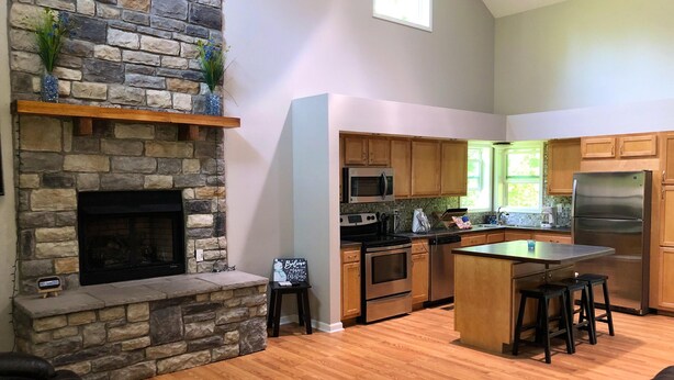 Una cocina moderna con chimenea de piedra, armarios de madera y una isla central.