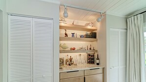 A kitchen with white cabinets, a countertop with various items, and a hanging light fixture.