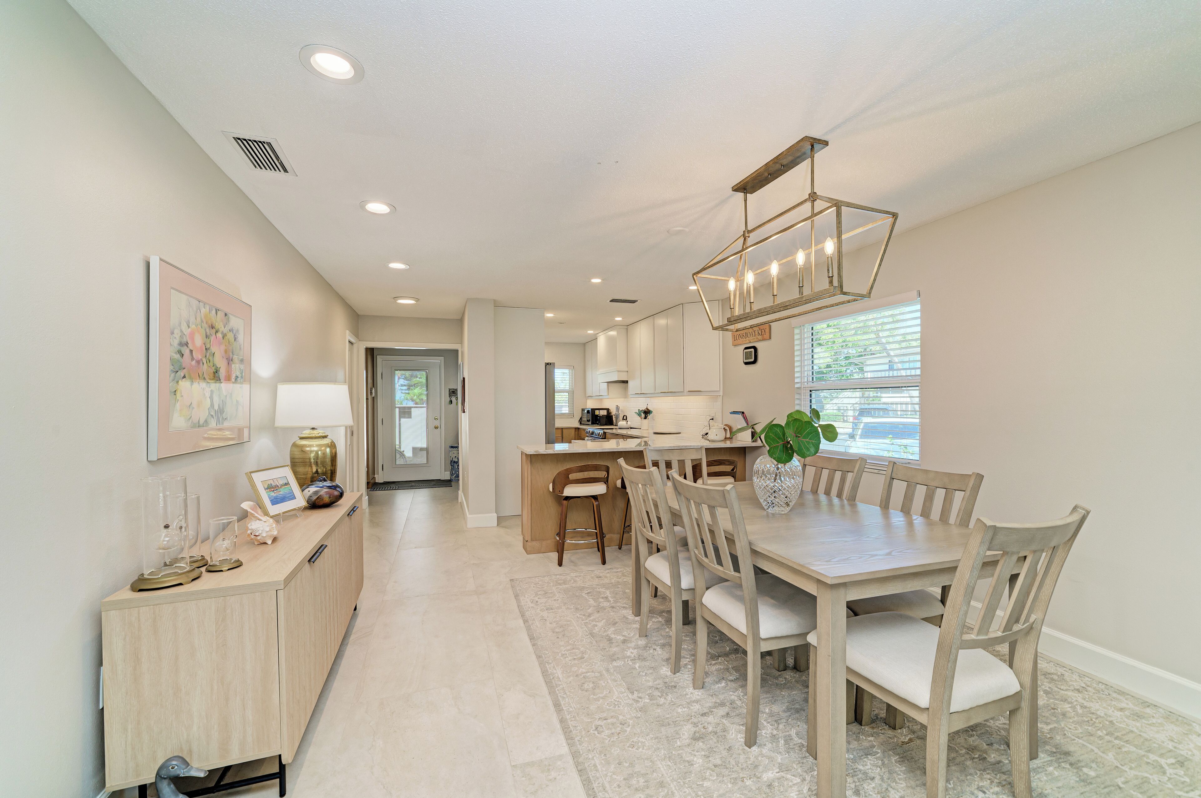 A spacious kitchen with a dining area, a light wooden cabinet, and a pendant light.
