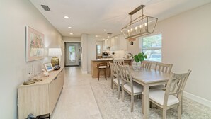 A spacious kitchen with a dining area, a light wooden cabinet, and a pendant light.