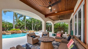 An outdoor patio with wicker furniture, a pool, and tropical plants. - Paradise Palm Villa- SEE OUR NEW POOL AREA AND OUTDOOR KITCHEN!  (Naples)