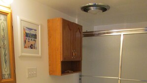 Un bagno con il water, un lavandino, armadietti in legno, un portasciuga e una cabina doccia.