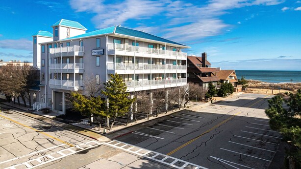 Un hôtel à plusieurs étages, doté de balcons, d’un parking et offrant une vue sur la plage.