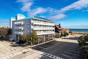 A multi-story hotel with balconies, a parking lot, and a view of the beach. - The Marylander Condo & Hotel (Ocean City)