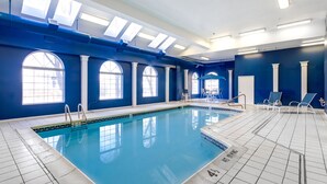 Une piscine intérieure à l’eau d’un bleu limpide, dotée de lucarnes et d’un sol carrelé.