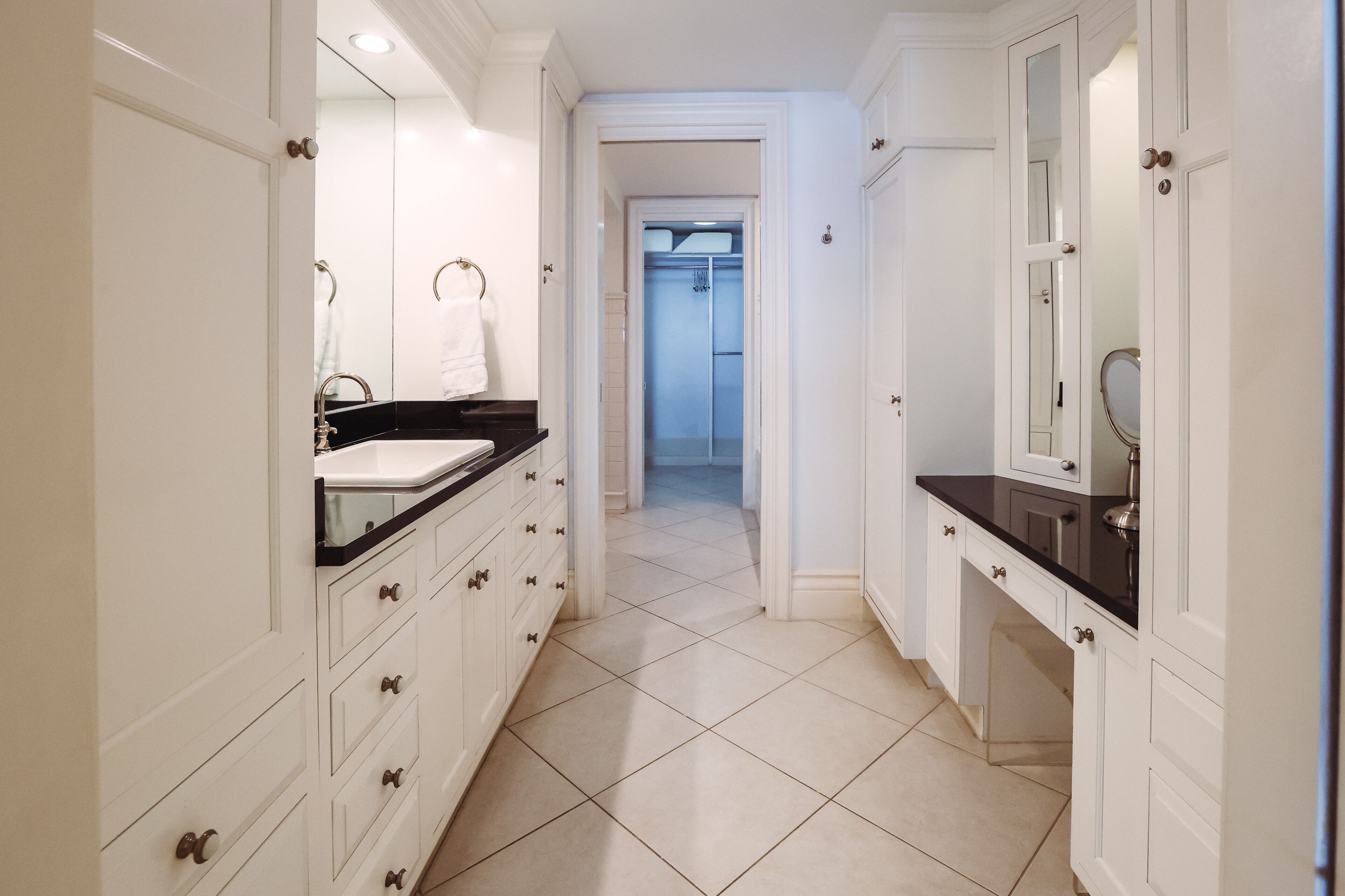 A modern bathroom with white cabinetry, a black countertop, and a tiled floor.