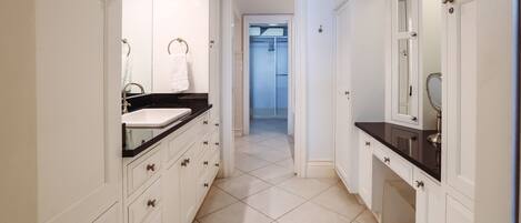 A modern bathroom with white cabinetry, a black countertop, and a tiled floor.