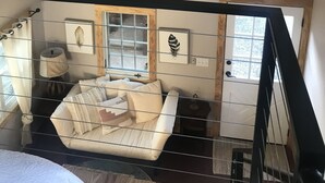 A spacious room with a high ceiling, a ceiling fan, a large window, and a staircase. - Beautiful Asheville Tiny Home Get-a-way (Asheville)