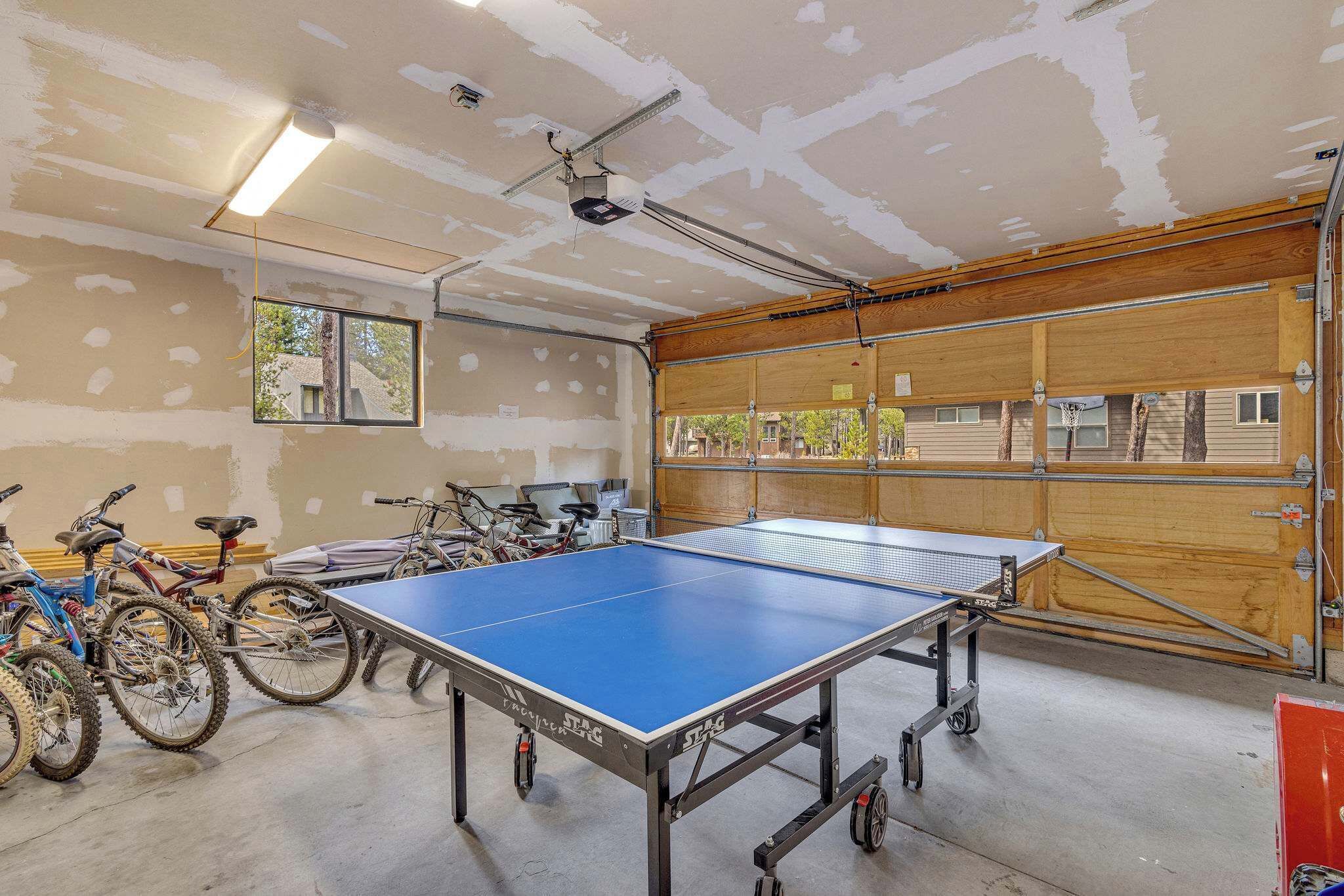 A spacious indoor area with a ping pong table, bicycles, and a large window.