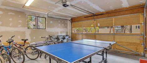 A spacious indoor area with a ping pong table, bicycles, and a large window.
