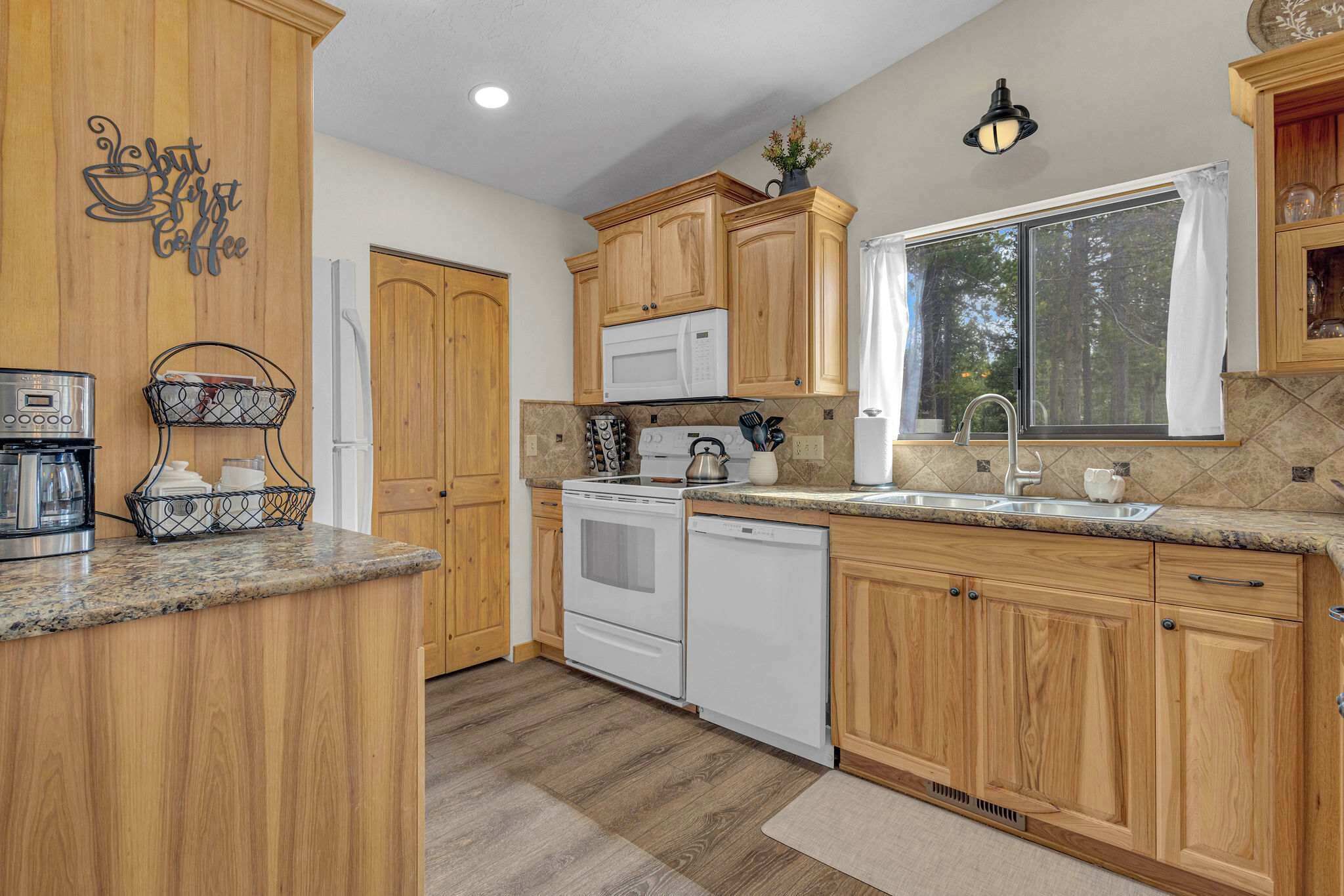 A kitchen with wooden cabinets, a microwave, stove, and a sink.