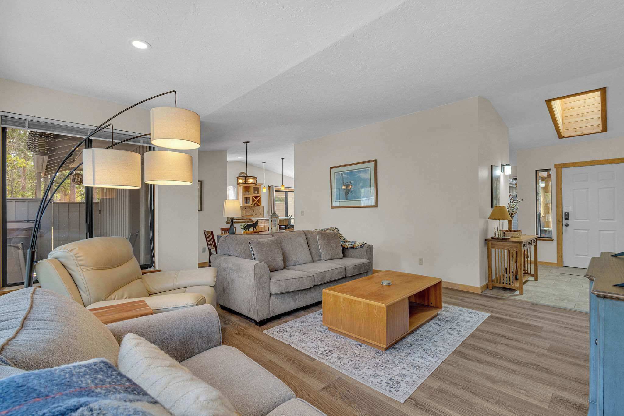 A modern living room with a sofa, a coffee table, and a dining area with a table and chairs.