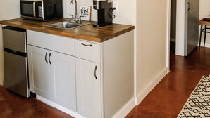 Une cuisine dotée d’un plan de travail en bois, d’un four à micro-ondes, d’une machine à café et d’une étagère où sont disposés des objets décoratifs.