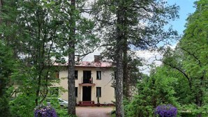A two-story house with a front entrance, surrounded by trees and a dirt path leading to it. - Peaceful Pernaja (Loviisa)
