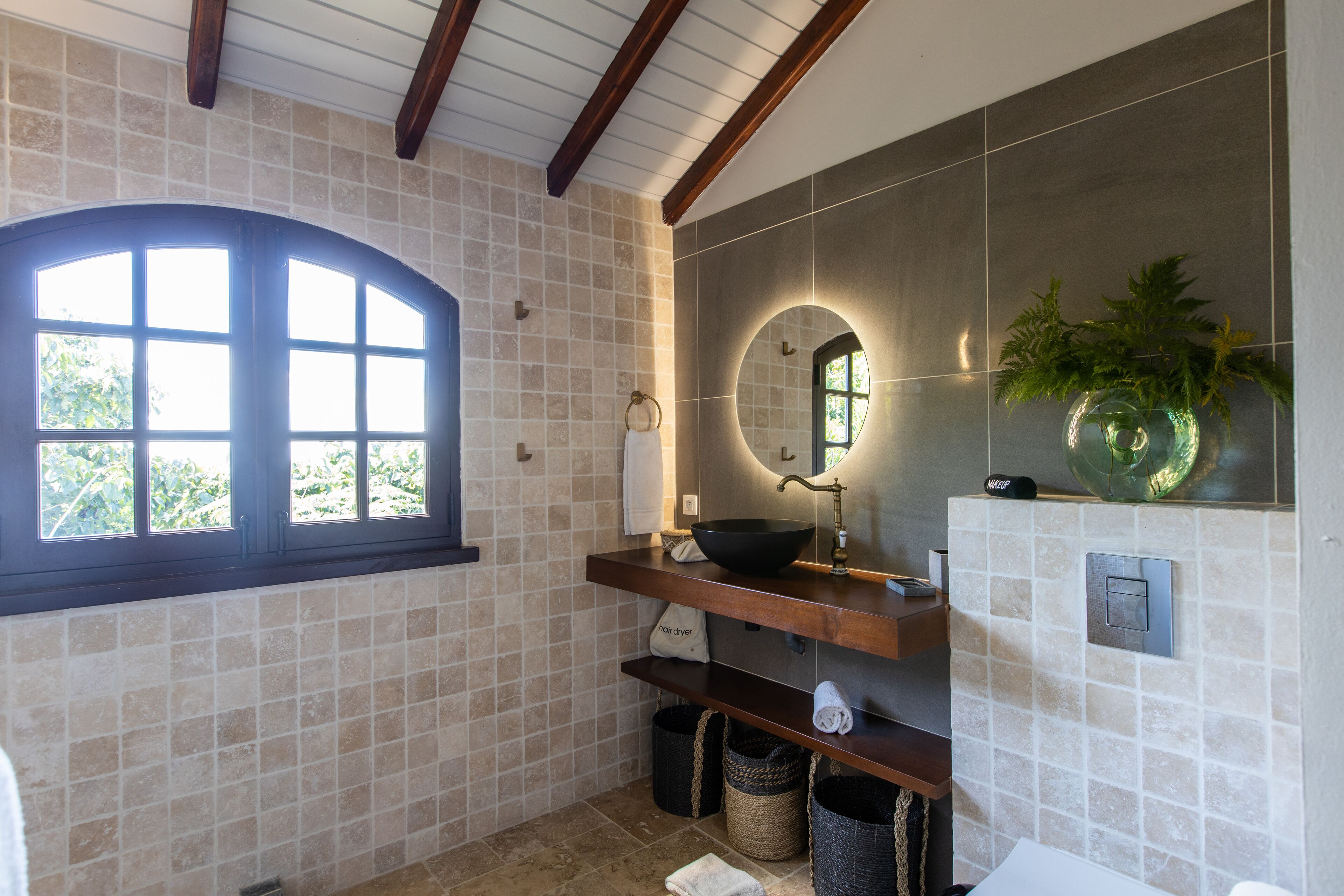 A bathroom with a large window, a sink with a mirror, and a towel rack.