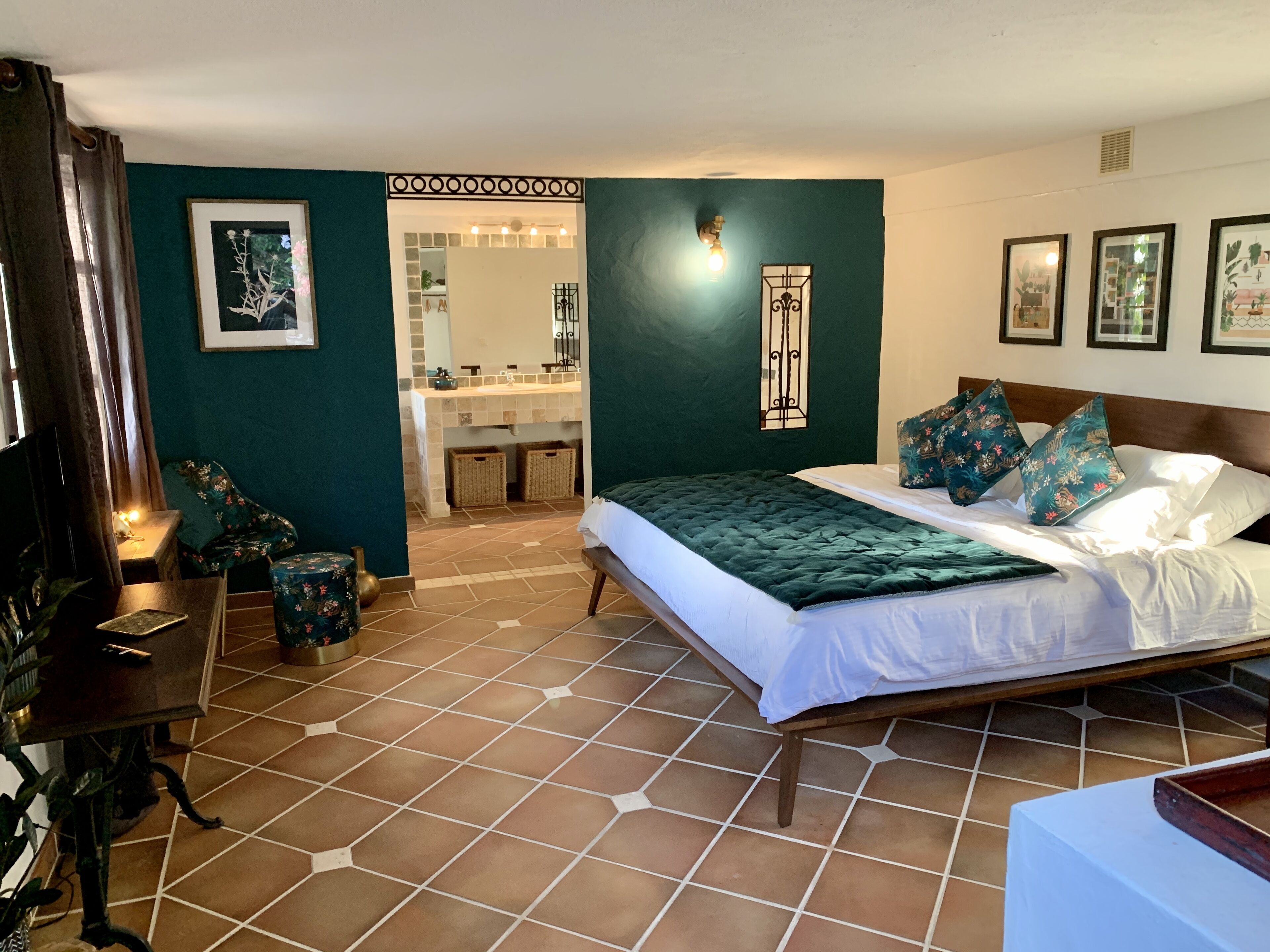 A bedroom with a bed, a nightstand, a dresser, and a bathroom visible through an open doorway.