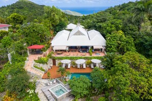A large, white-roofed villa with a pool, surrounded by lush greenery and a view of the ocean. - The Paradise Peak - Adults Only (Marigot)