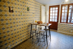 Une cuisine avec un mur décoré de motifs, une table avec des tabourets et une fenêtre donnant sur un paysage agréable.