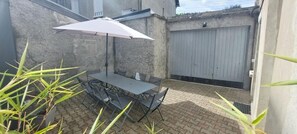 Une terrasse avec une table et des chaises, un parasol et une porte de garage.