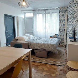 Une chambre à coucher comprenant un lit, un bureau, une chaise, une petite table et un téléviseur.