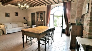 Un coin repas avec une table et des chaises en bois, un canapé blanc et une grande fenêtre avec des rideaux.