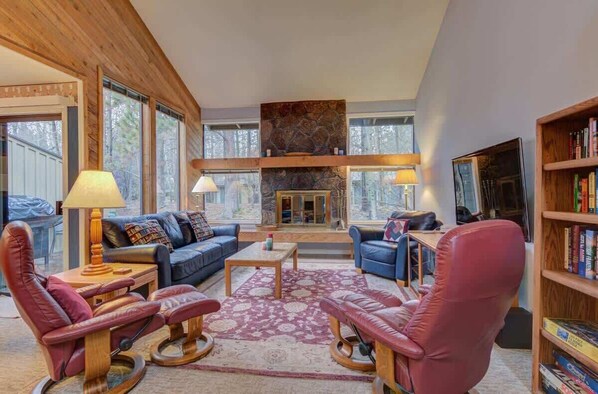 A spacious living room with leather sofas, a fireplace, and a bookshelf. - Near Marina, stables, great location sleeps 8 (Sunriver)