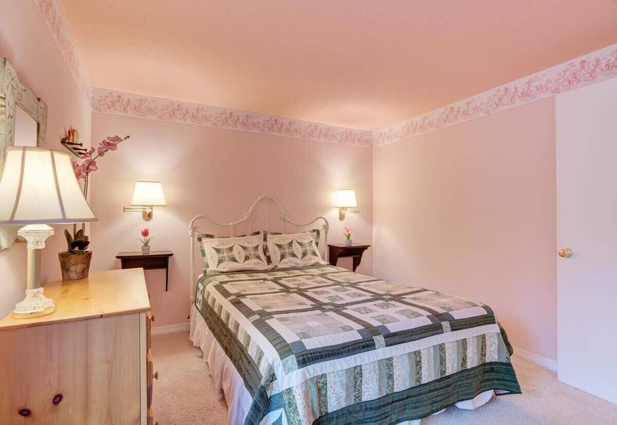 A bedroom with a bed, two bedside lamps, a nightstand, a dresser, and a mirror.