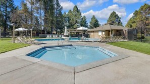 A rectangular pool with lounge chairs and umbrellas, surrounded by a fence and trees. - Near Marina, stables, great location sleeps 8 (Sunriver)