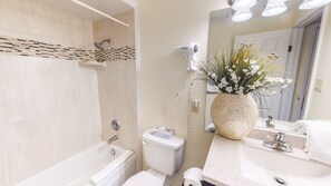 Un baño con bañera, inodoro, lavamanos y espejo.