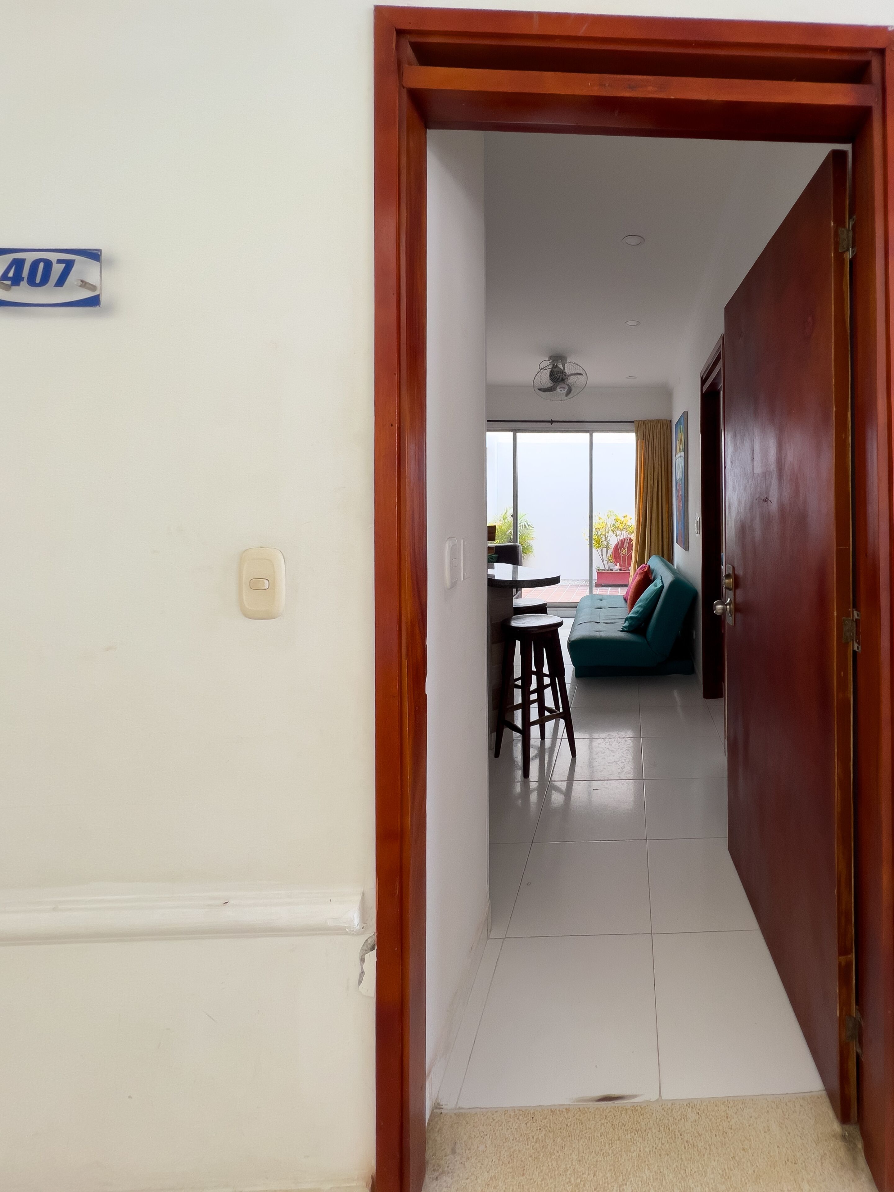 A hallway leading to a living area with a sofa, a table, and a chair.