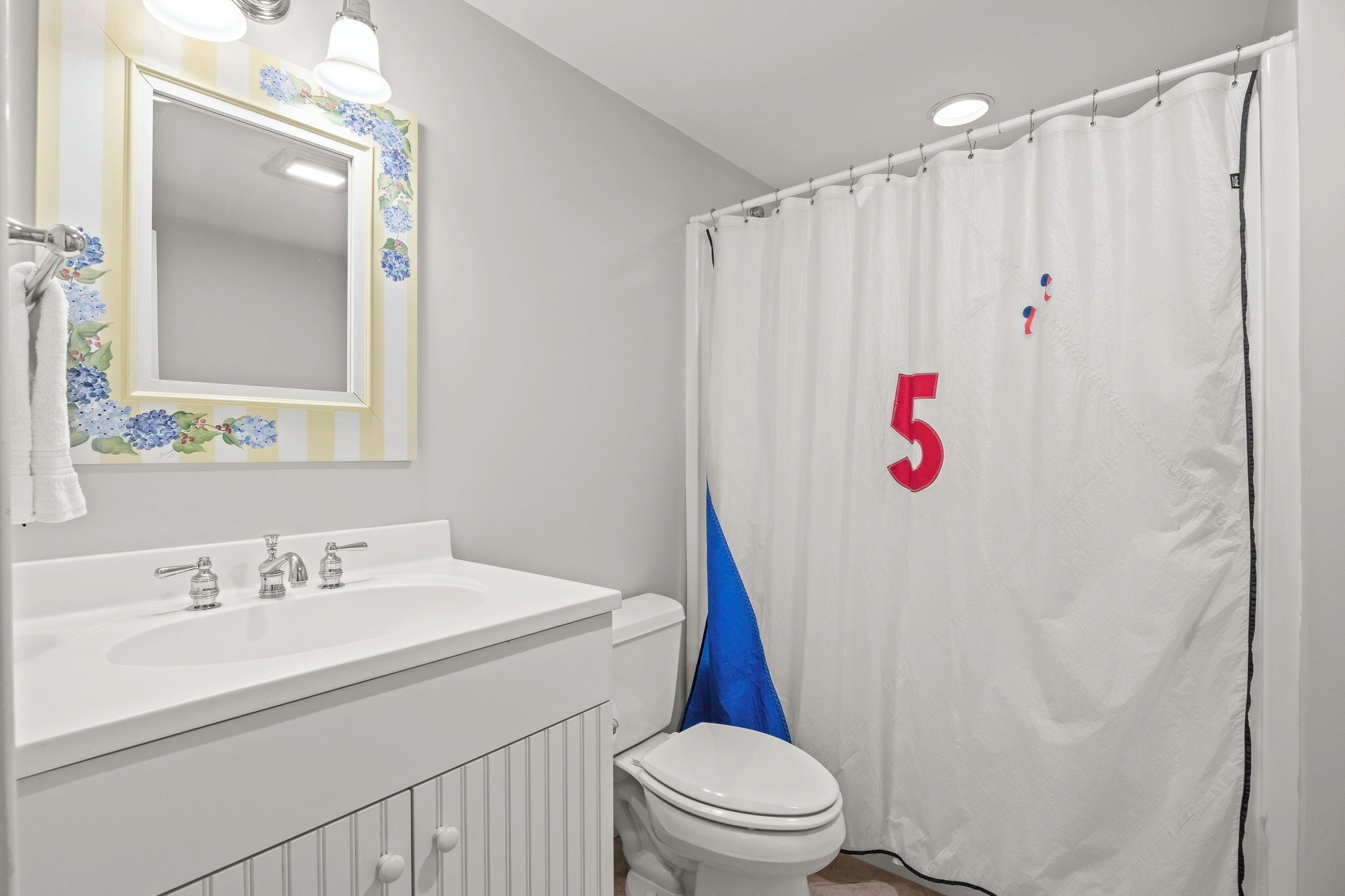 A bathroom with a white sink, a toilet, and a shower curtain with a number 5 on it.