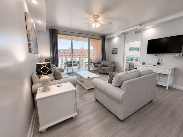 A modern living room with a sofa, coffee table, and TV stand. - 2128 Pool & Beach views,  w/ two parking passes, spectacular lagoon-style pool (Panama City Beach)
