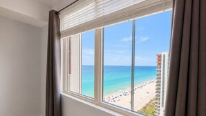 Una stanza con una grande finestra che si affaccia su una spiaggia e un edificio.