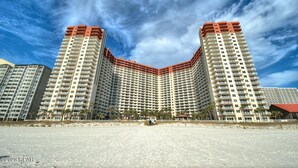 Un hotel di grandi dimensioni con facciata curva, numerosi balconi e vista sulla spiaggia.